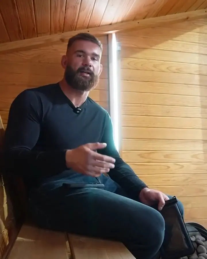 Daniel Manasoiu, founder of Sauna Safe Case, sitting in a sauna with the case